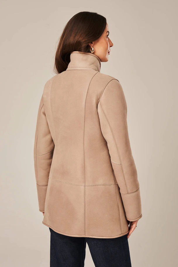Woman wearing a beige coat against a plain background