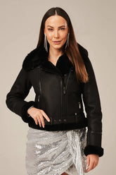 Woman wearing a black leather jacket with fur trim on a beige background