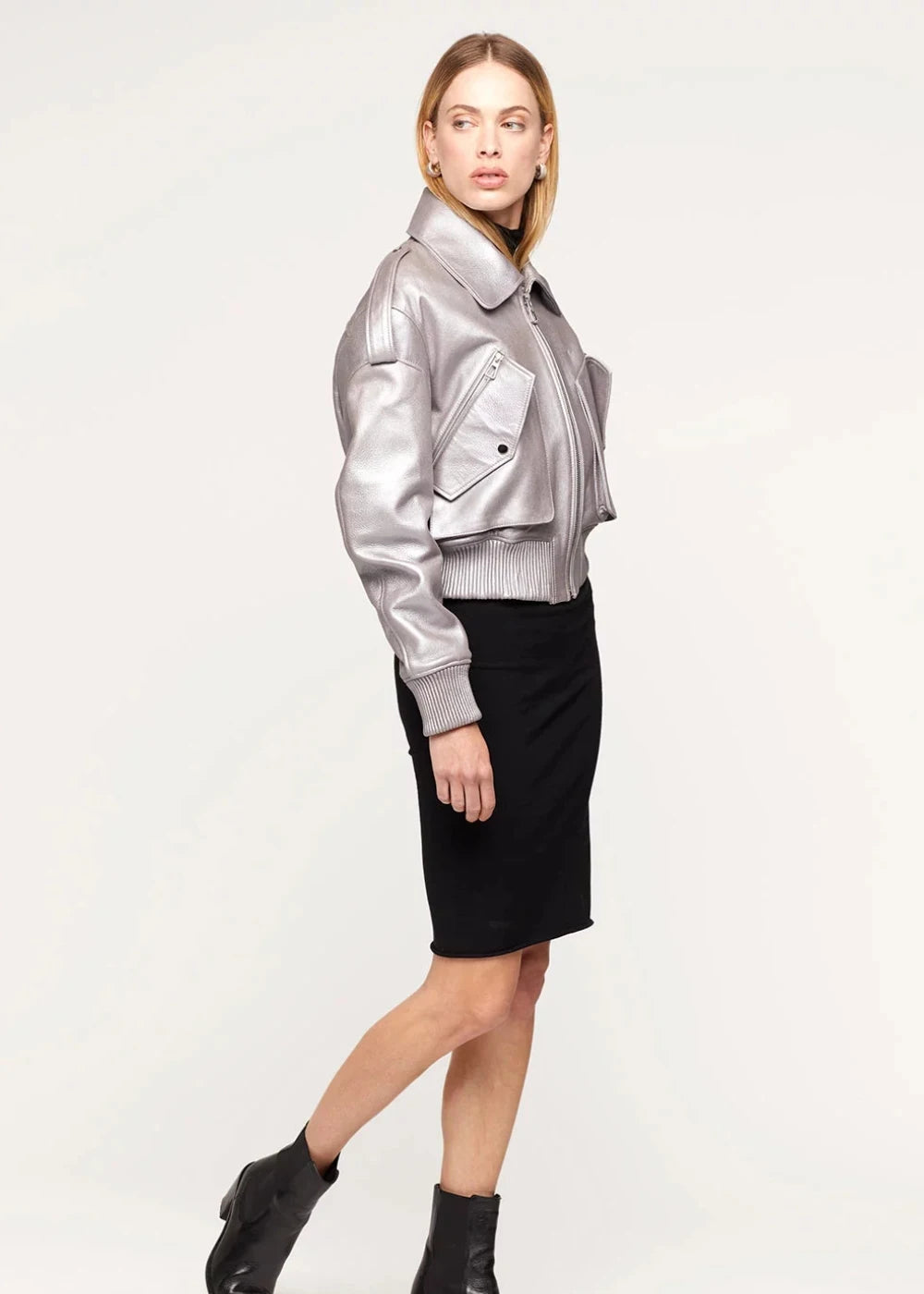 Woman wearing a silver jacket and black skirt on a white background