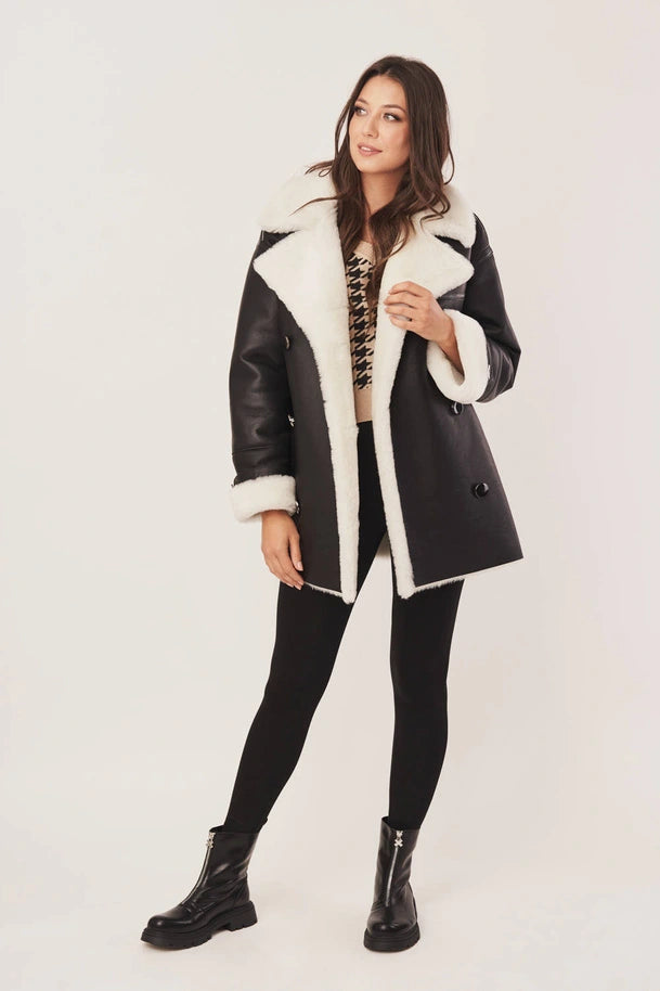 Woman wearing a black and white shearling coat on a white background