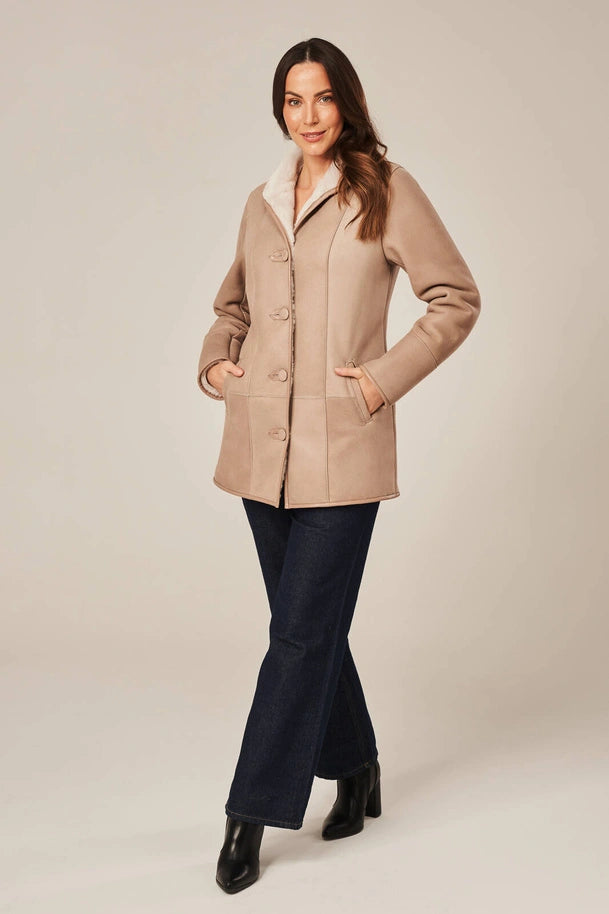 Woman wearing a beige coat on a plain background