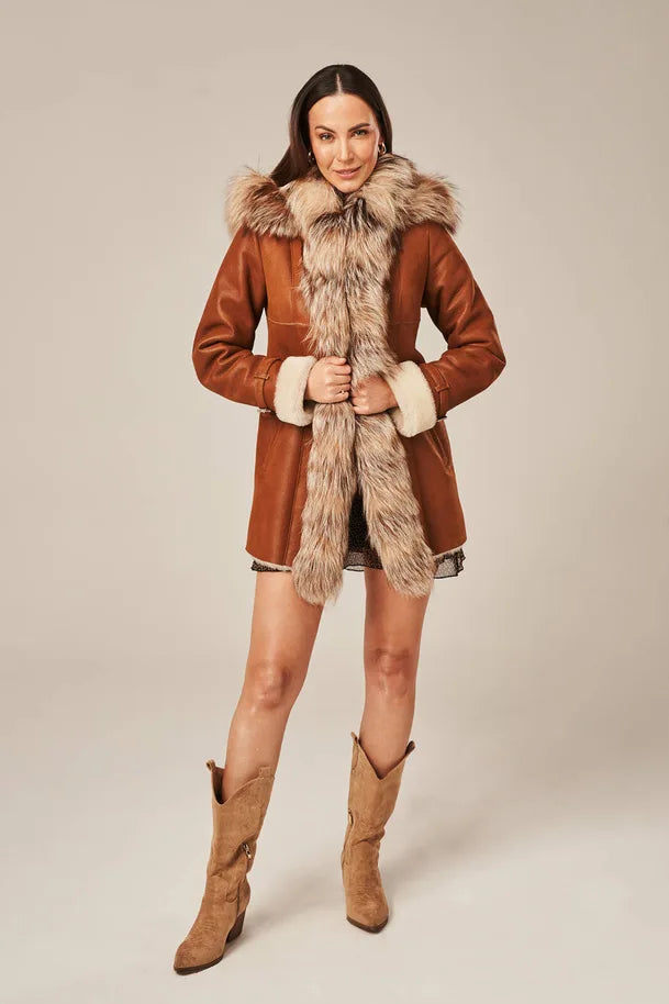 Woman wearing a brown coat with fur trim and matching boots on a beige background