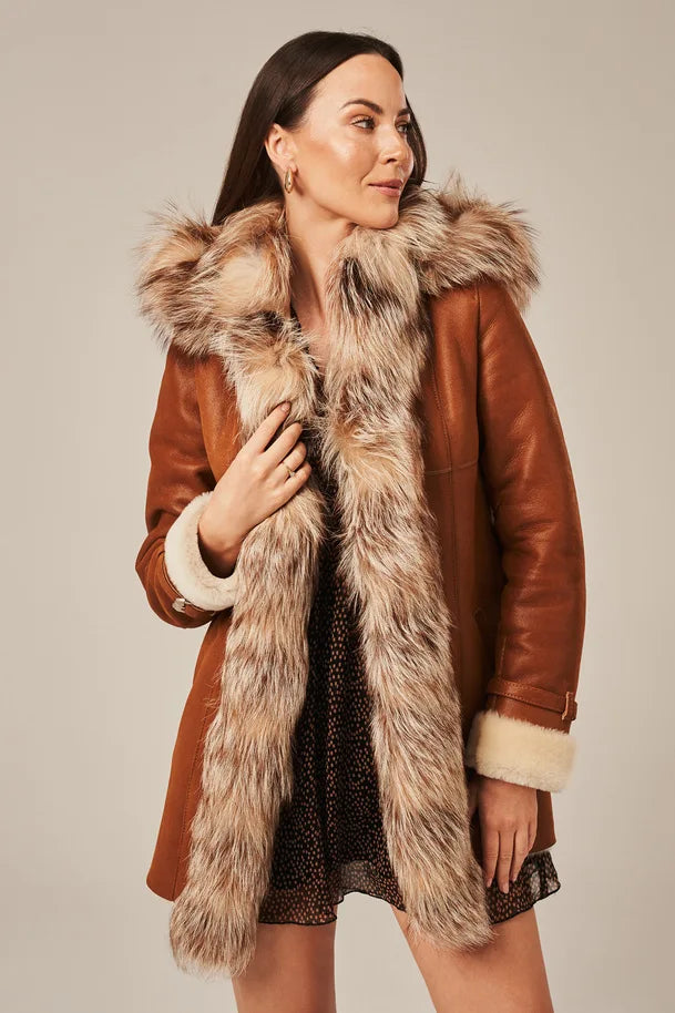 Woman wearing a brown leather coat with fur trim on a neutral background