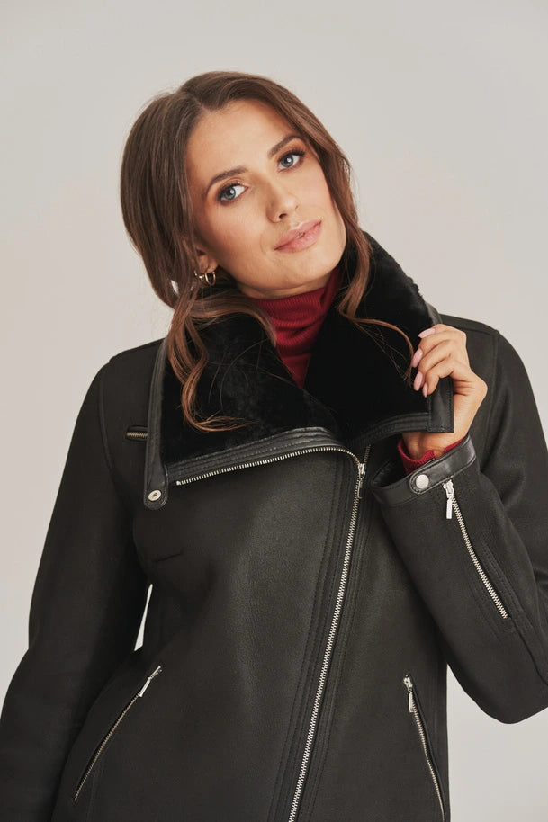 Woman wearing a black coat with a fur-lined hood against a plain background